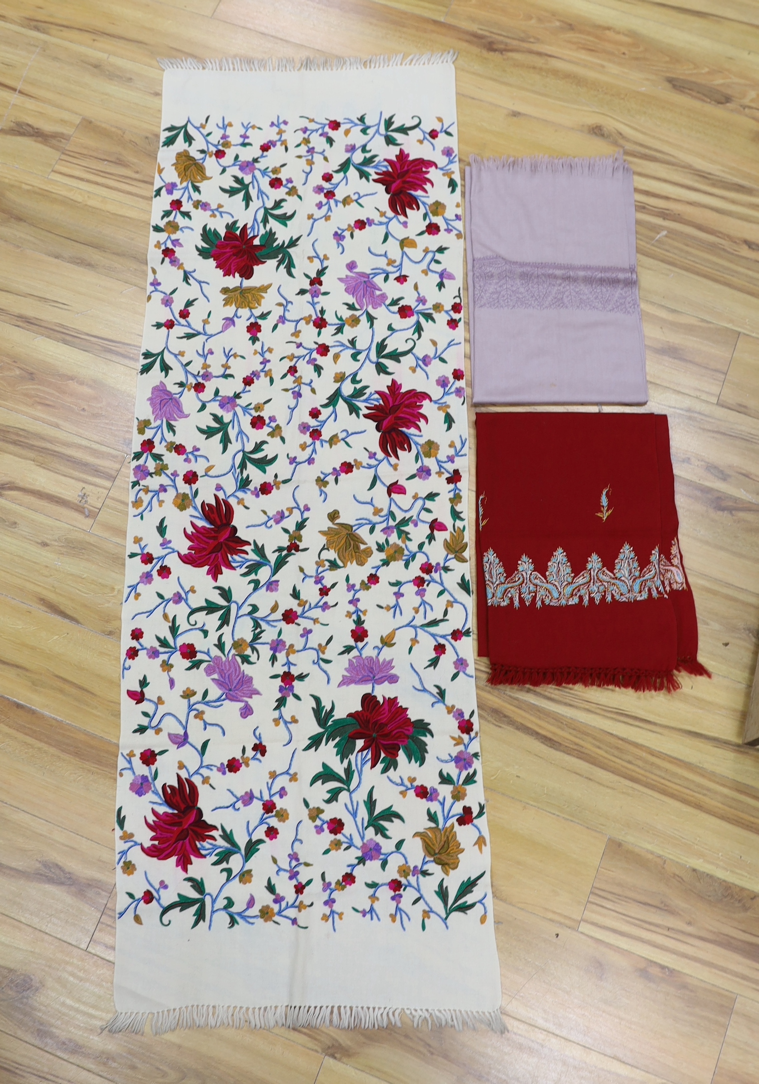 Three Kashmir scarves: a cream floral multicoloured silk embroidered stole, a lilac embroidered stole and a maroon multi coloured embroidered stole